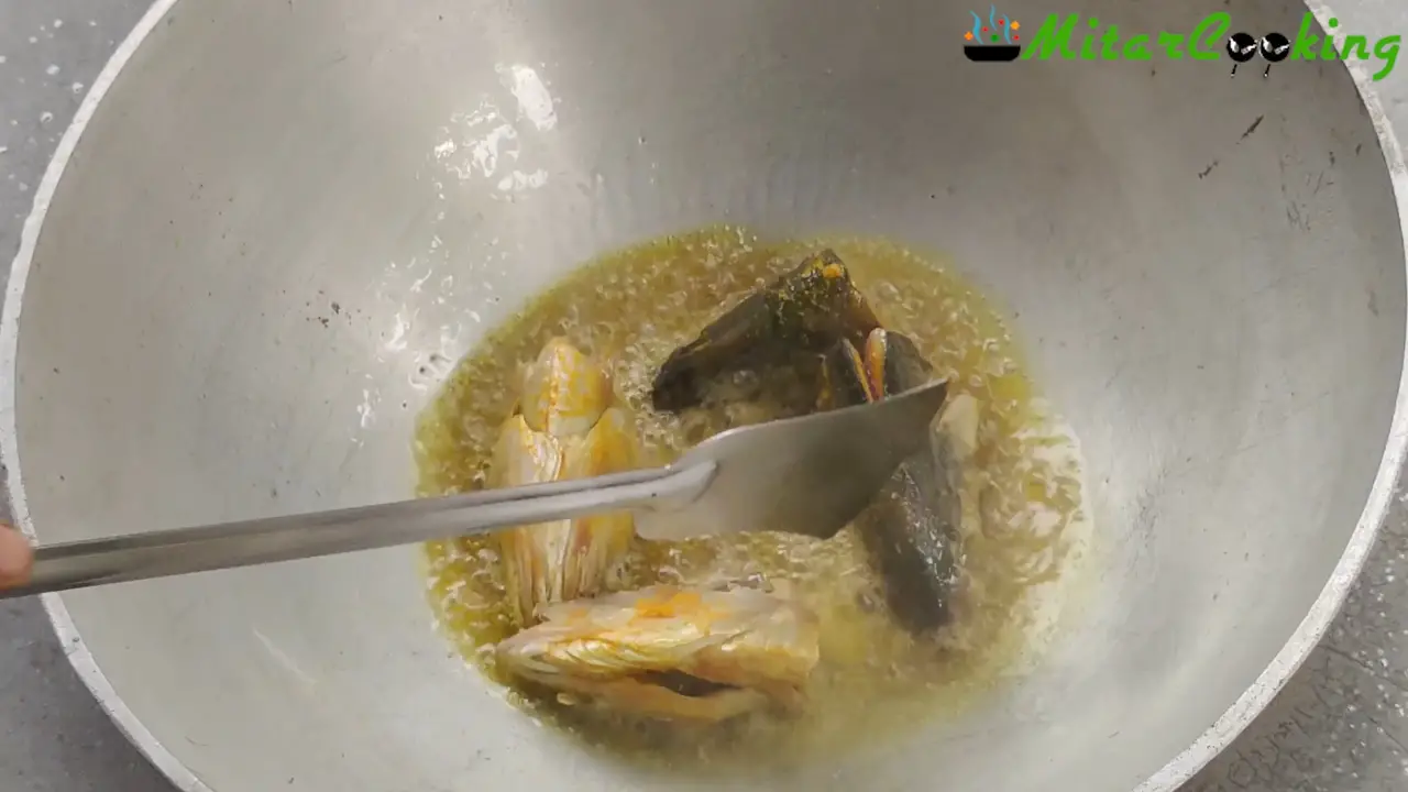 Sliding the hilsa heads one by one into the smoking oil.