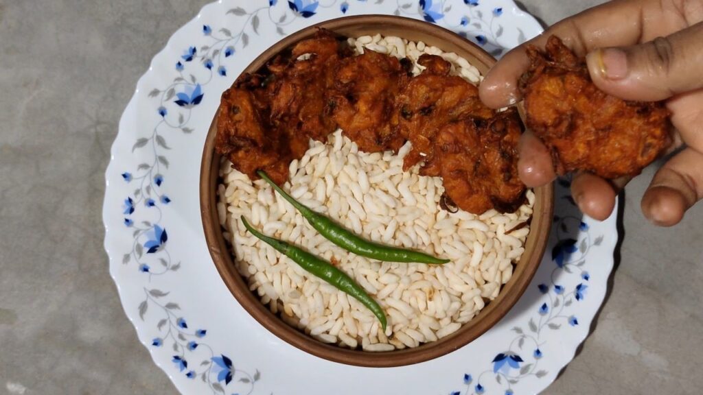 Serve crispy onion pakoda hot with muri and green chilli