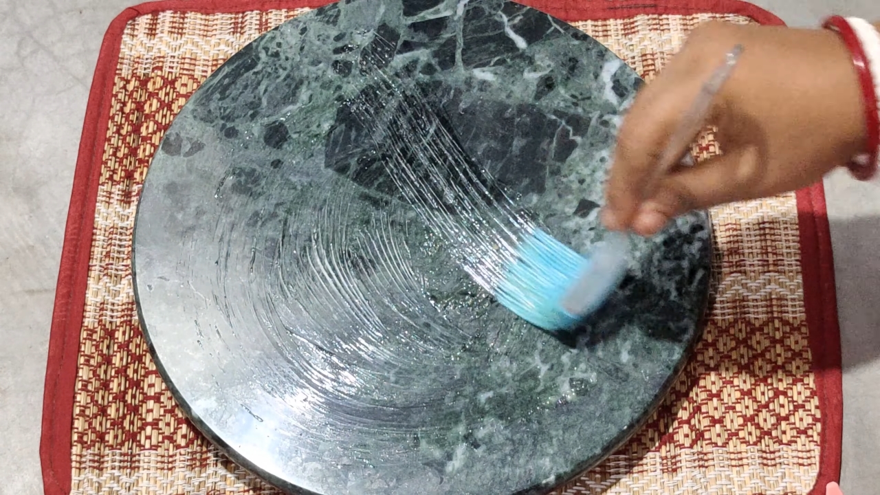 Brushing ghee (fortified butter) on a granite surface.