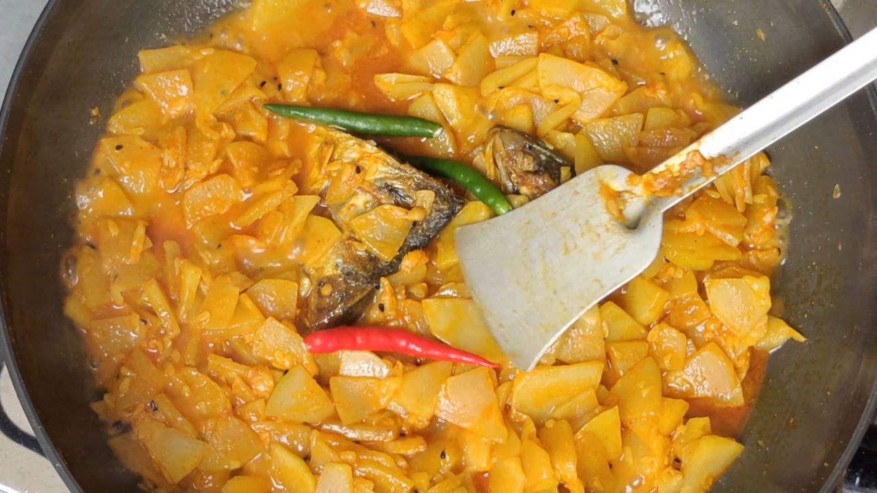 Adding green chili in hilsa head with ash gourd