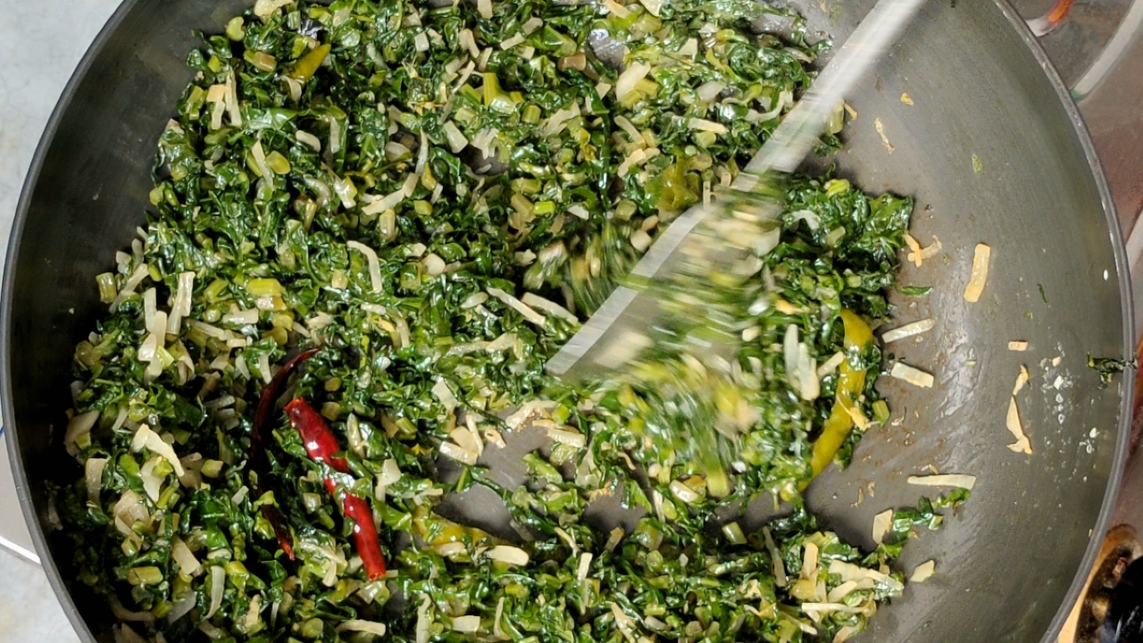 Stir frying the greens continuously
