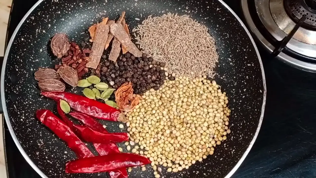 Putting 5 pieces of dry red chillies, 2 tbsp coriander seeds, 1 tbsp cumin seeds, ½ tbsp black pepper, 5 small cinnamon sticks, ½ tbsp cloves, 8 pods of green cardamom, 4 pods of black cardamom, and 1 small piece of mace in a frying pan
