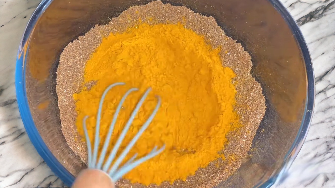 Adding turmeric powder to the ground mixture