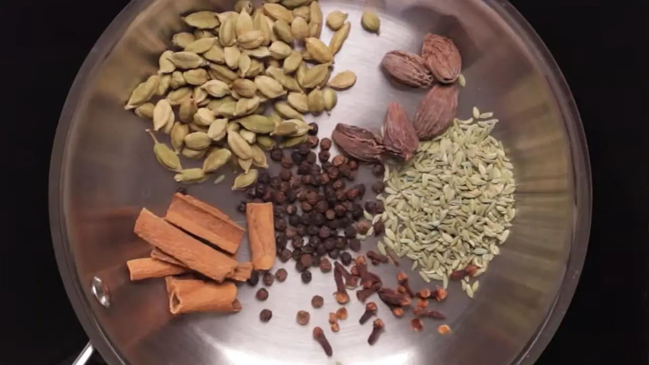 Heaing ½ cup of green cardamom, 5 pieces of black cardamom, 2 tbsp of black pepper, 2 tbsp of fennel seeds, 1 tbsp cloves, and 6 small pieces of cinnamon sticks in a pan.