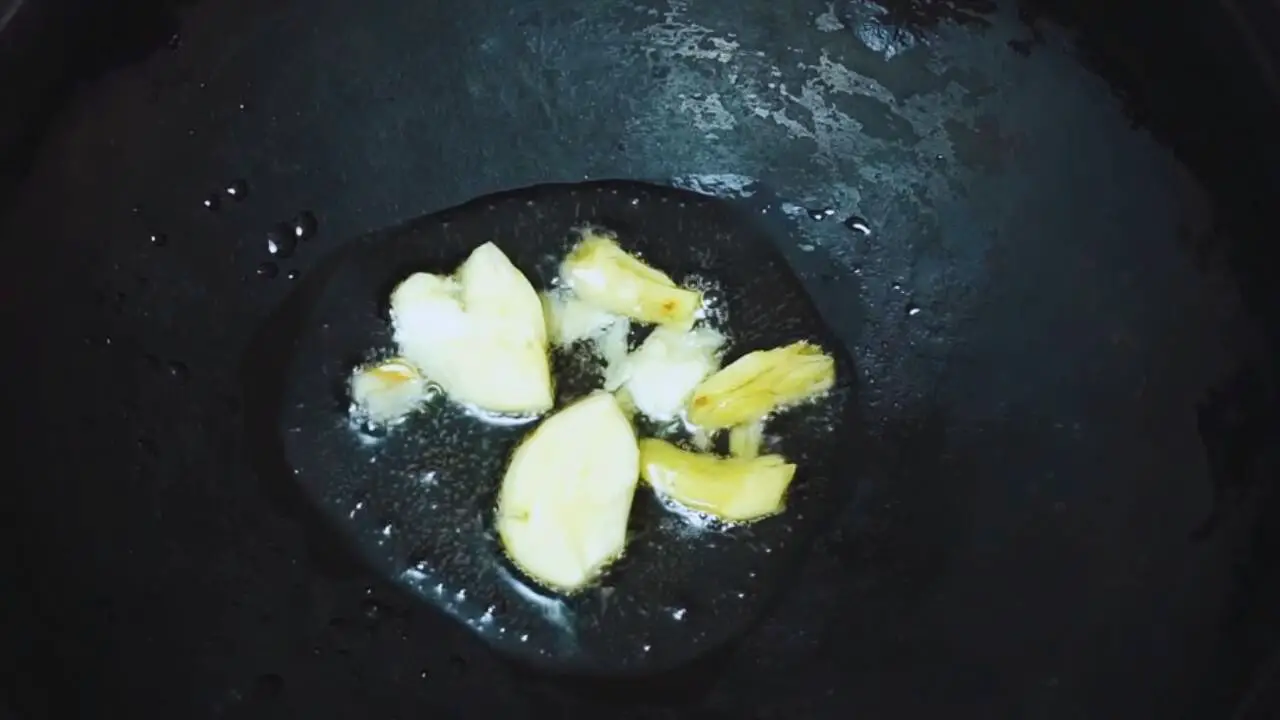 Adding 2 pieces of smashed garlic and 1 piece of ½-inch size ginger