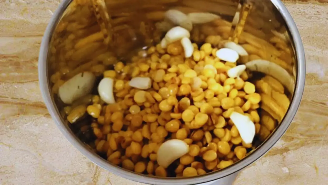 Adding 10 garlic cloves to the content in the grinder