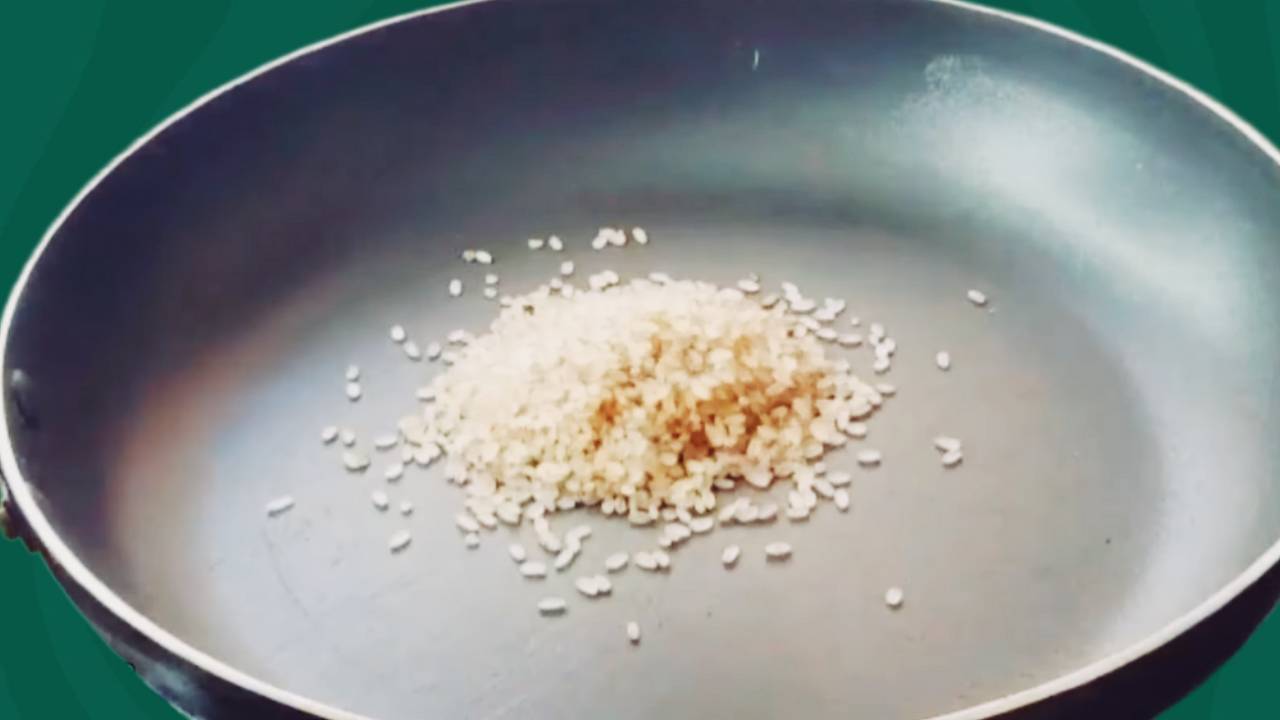 Pouring 2 tbsp of brown rice into the frying pan