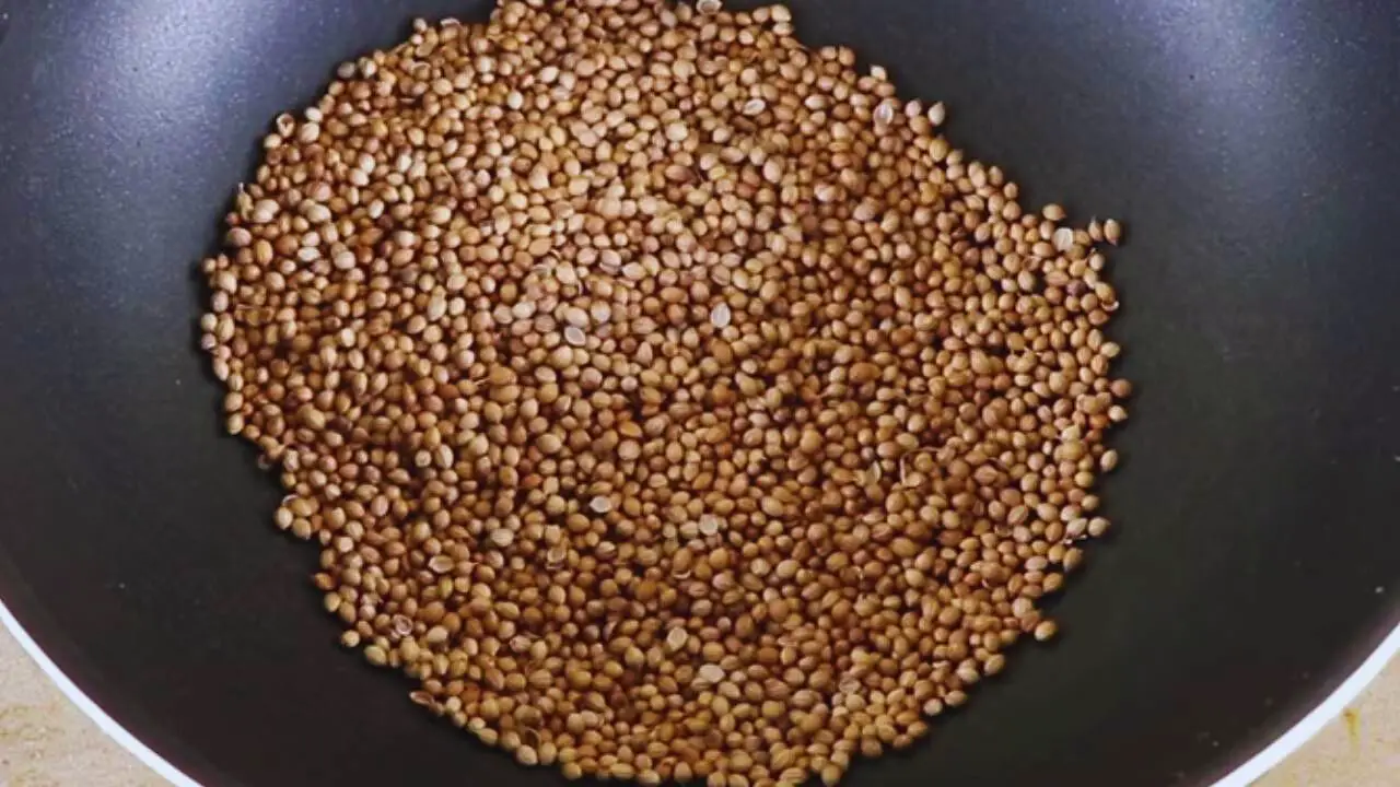 Putting 60 gms of coriander seeds (dhania) into the wok
