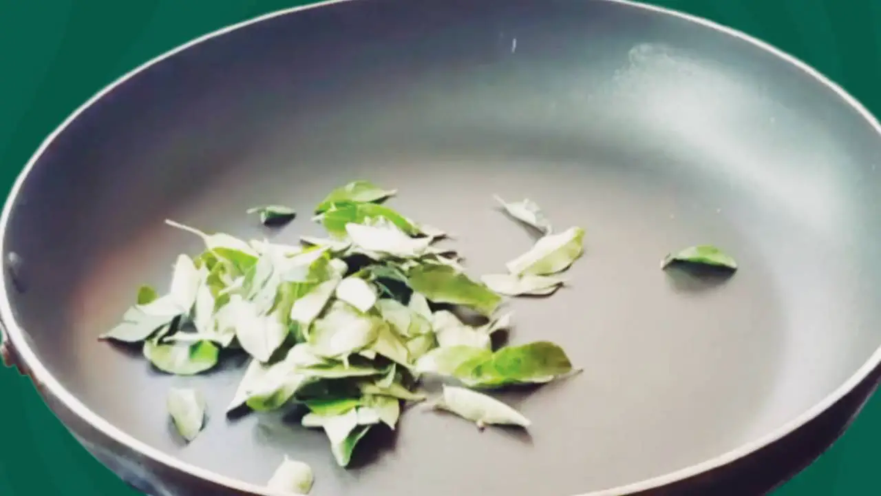 Putting 1 tbsp of curry leaves into the pan