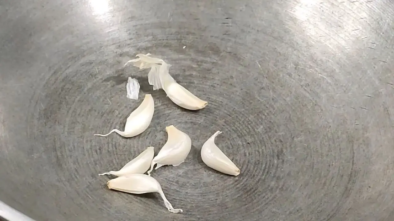 Putting 6 pieces of garlic in the wok