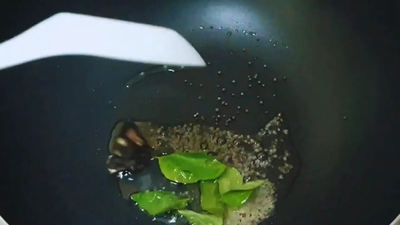 Putting ½ tsp mustard seeds, ¼ tsp asafetida, 6 pieces of curry leaves, and 1 small piece of tamarind