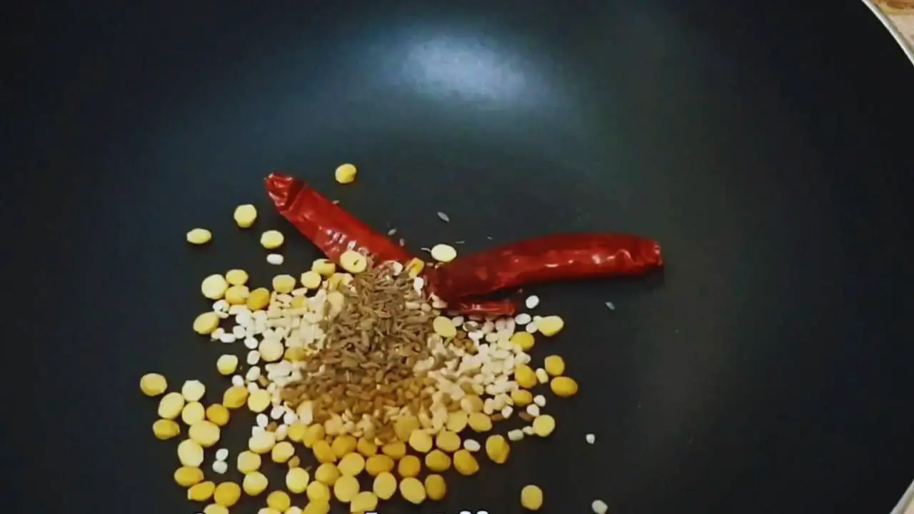 Putting two dry red chilies, ½ tsp cumin seeds, 1 tsp chickpea lentil (chana dal), 1 tsp black gram split (urad dal), and ¼ tsp fenugreek seeds in the pan
