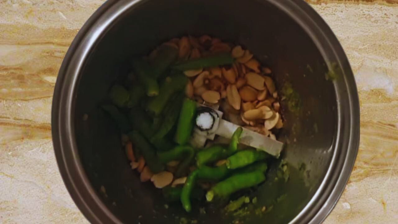 Putting ½ cup of roasted peanuts, 6 to 8 pieces of fresh green chilies, each broken in half, and ½ tsp of normal table salt in grinder
