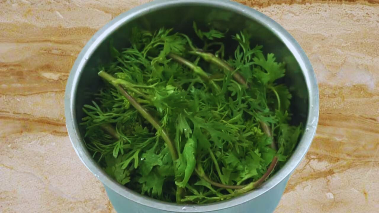 Putting 1 cup of fresh and green coriander leaves into the grinder