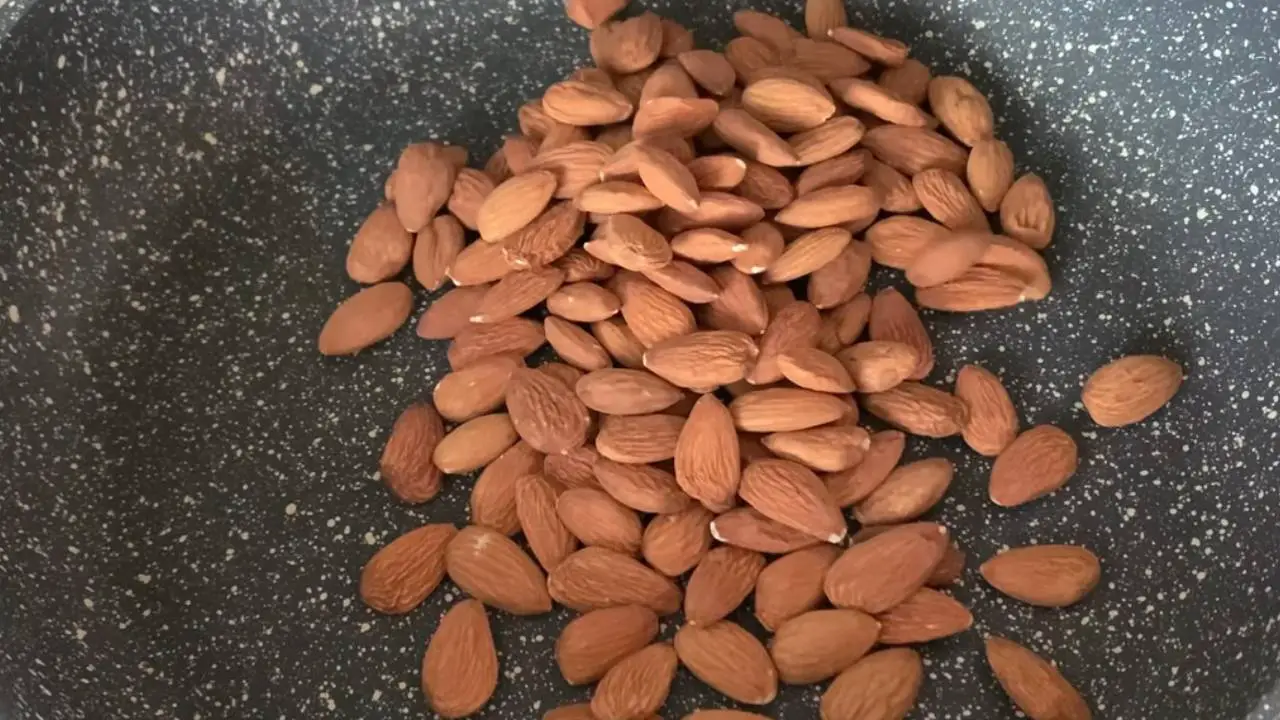 Putting a cup of almonds in pan