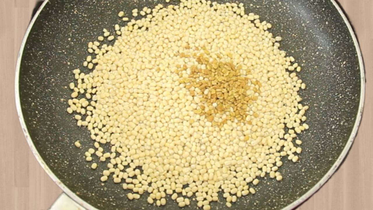 Pouring the de-husked black gram split and 1 tsp of fenugreek seeds into the hot pan