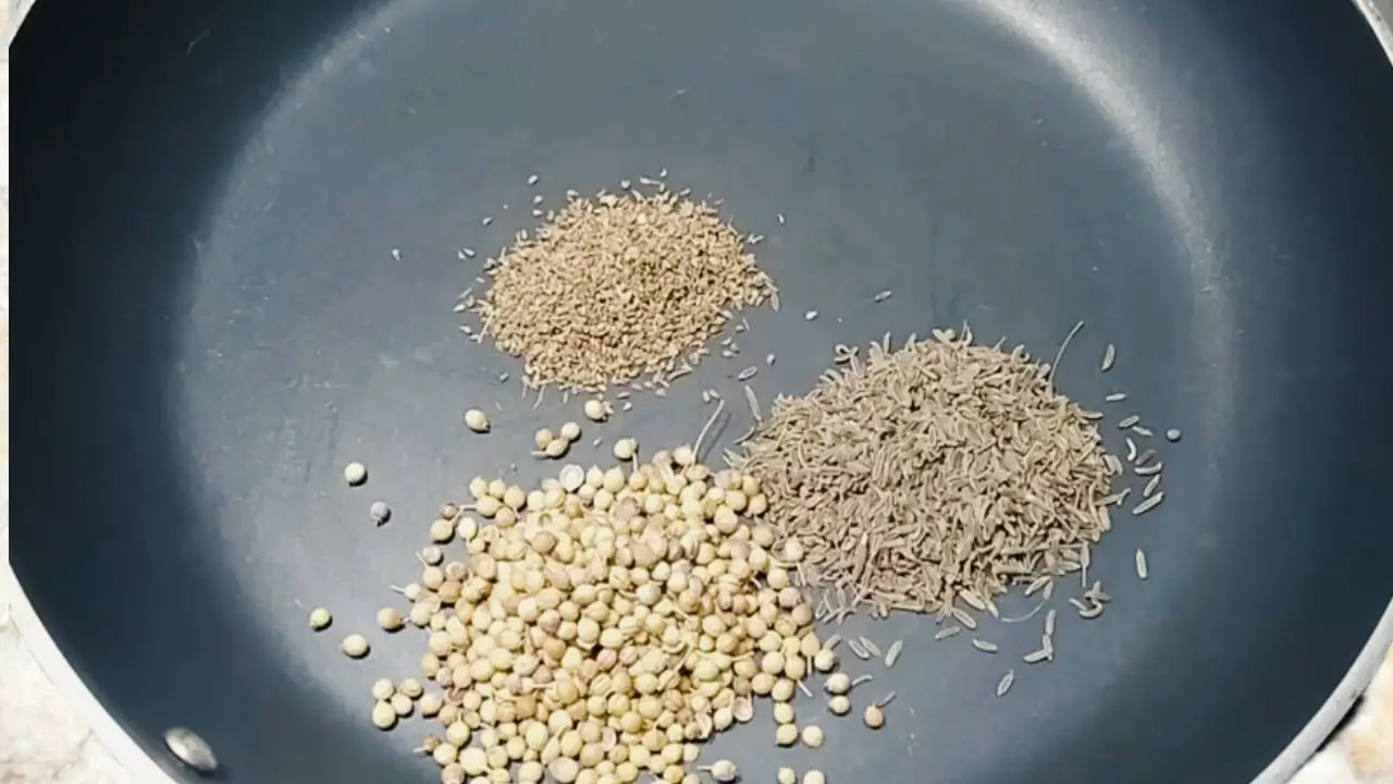 Putting 1 tsp of cumin seeds, 1.5 tsp of coriander seeds, and ½ tsp of carom seeds or ajwain in a pan