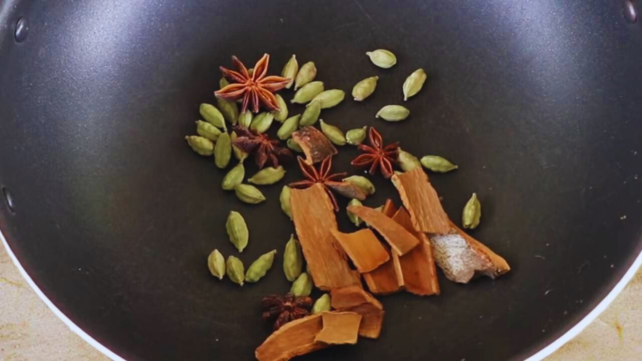 Putting 10 gms of green cardamom (elaichi), 10 gms of small 1-inch cinnamon (dalchini) sticks, and 5 pieces of star anise (chakra phool) into the wok