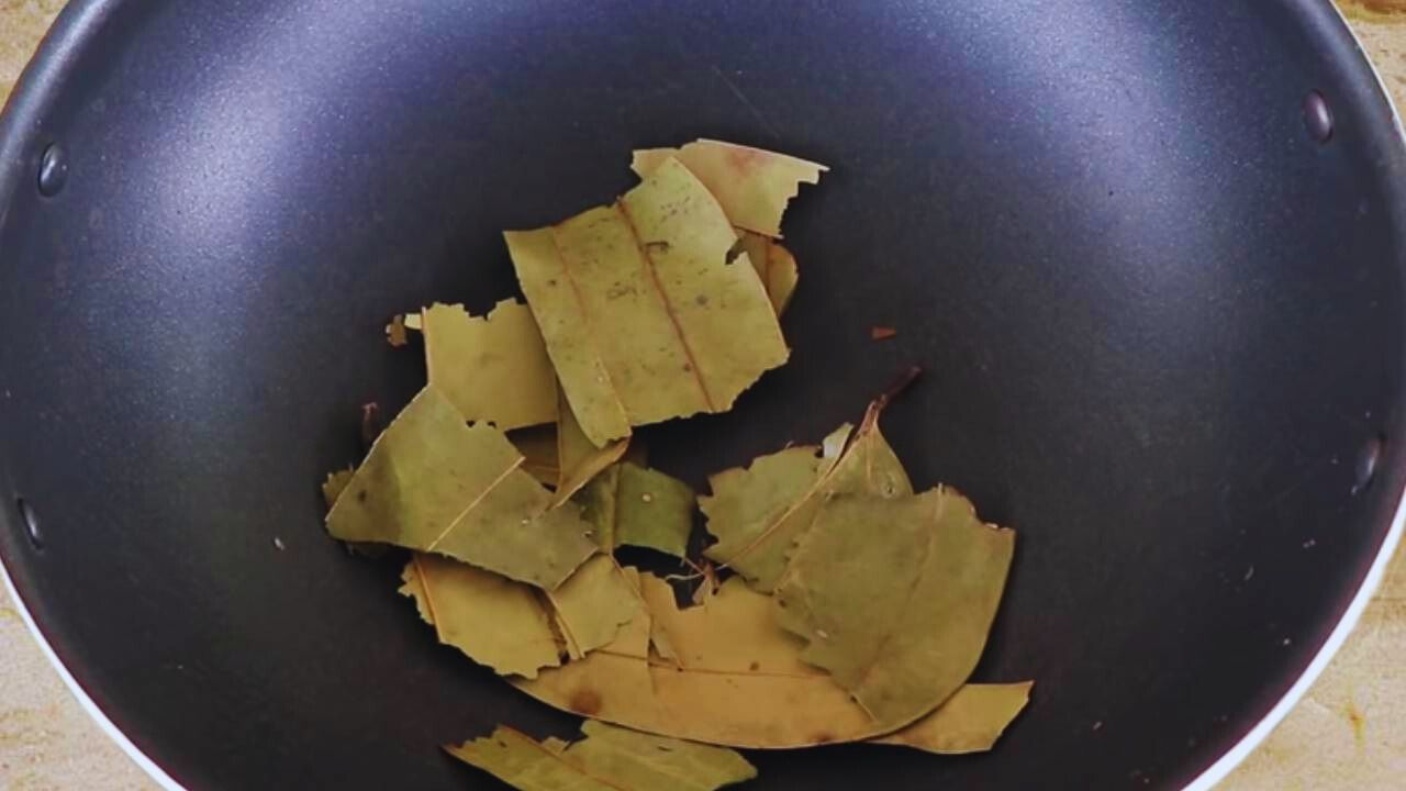 Putting 3 medium-sized bay leaves (tej patta) into the wok