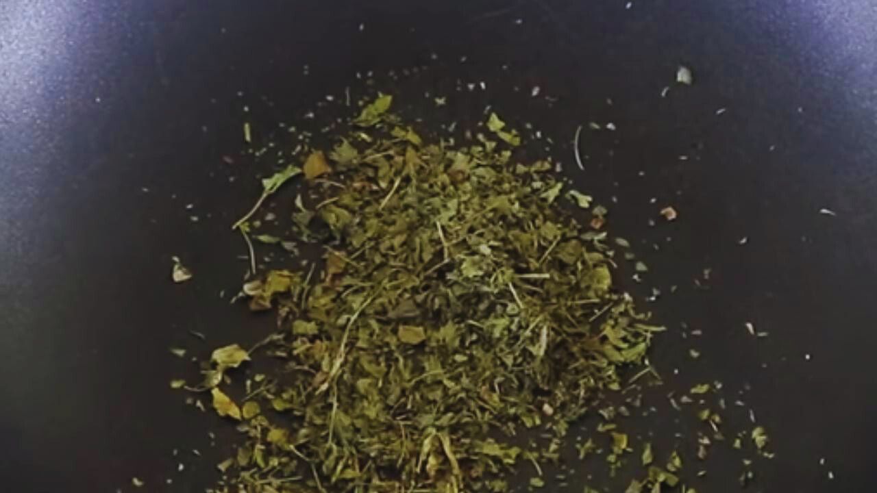 Putting 1 tbsp of dry fenugreek (kasturi methi) leaves into the wok
