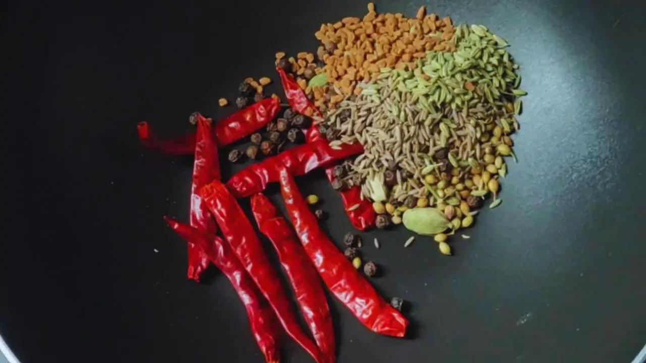 Putting 8 pieces of dry red chilies, 8 pods of green cardamom, 2 tsp of coriander seeds, 1 tsp of black pepper, 1 tsp cumin seeds, ½ tsp of fennel seeds, and ½ tsp of fenugreek seeds in the wok