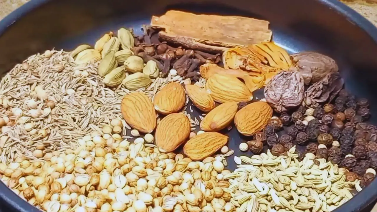 Putting 8 pieces of almonds, 1 tsp of black pepper, 2 pieces of black cardamom pods, 2 pieces of mace, ½ a piece of nutmeg, 2 cinnamon sticks of medium size, ½ tsp of cloves, about 12 pieces of green cardamom pods, 1 tbsp of cumin seeds, 2 tbsp of coriander seeds and 1 tsp of fennel seeds into the pan