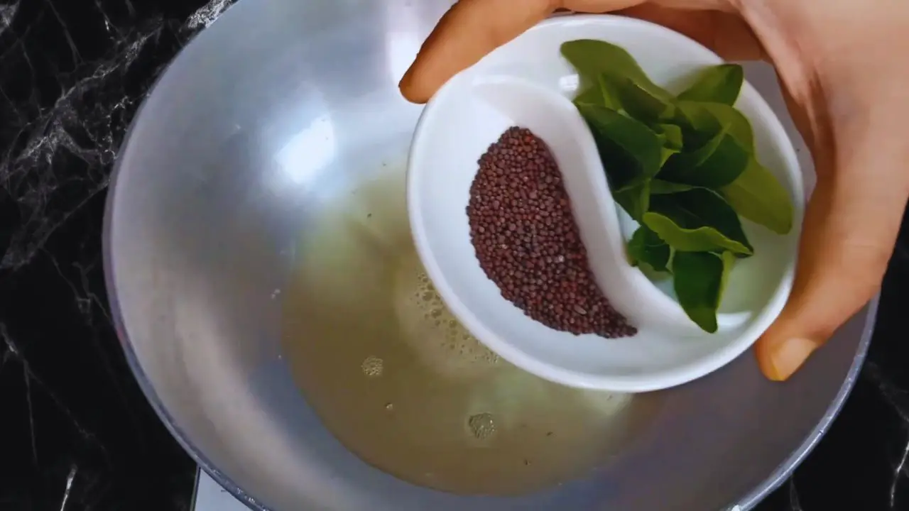Adding curry leaves and mustard seeds to the wok