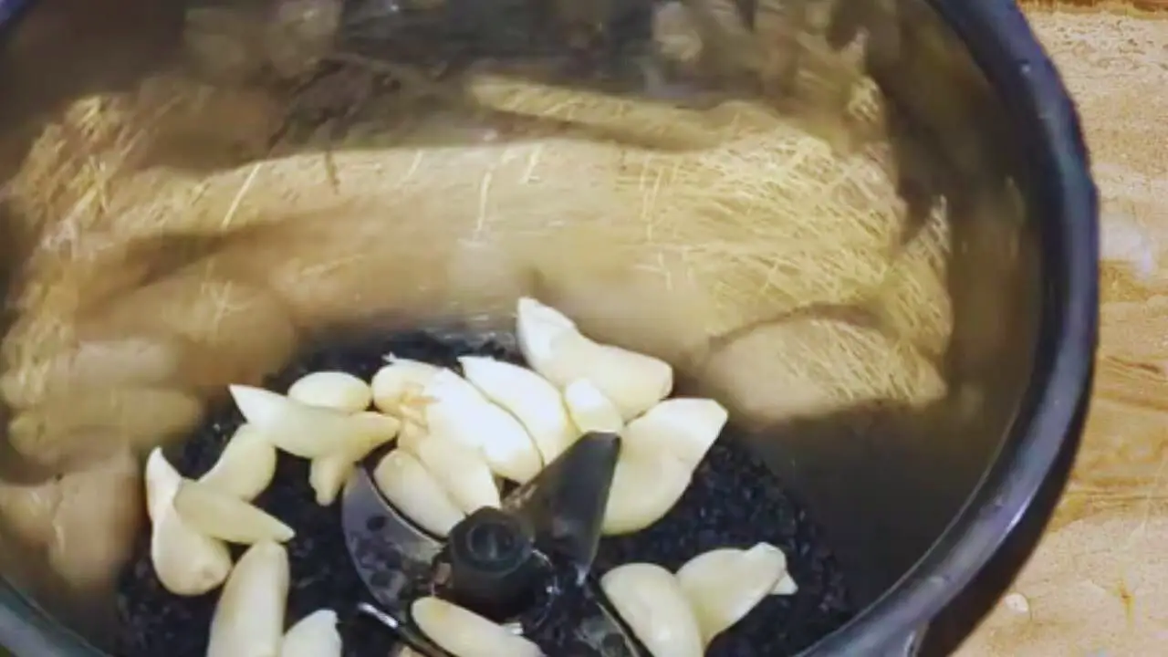 Adding fresh garlic into the grinder with black sesame seeds to make the chutney paste