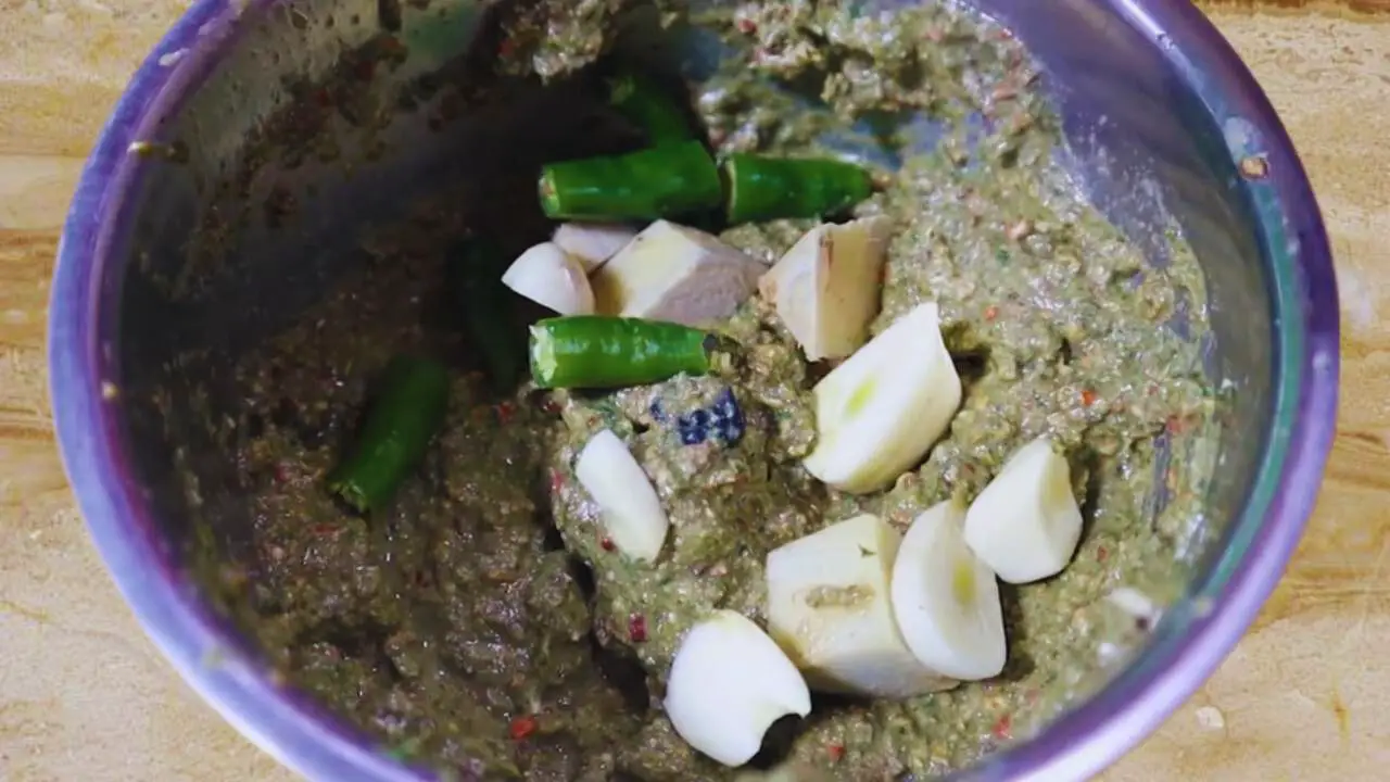 Adding 2 cloves of sliced garlic, 3 pieces of fresh green chilies broken in half