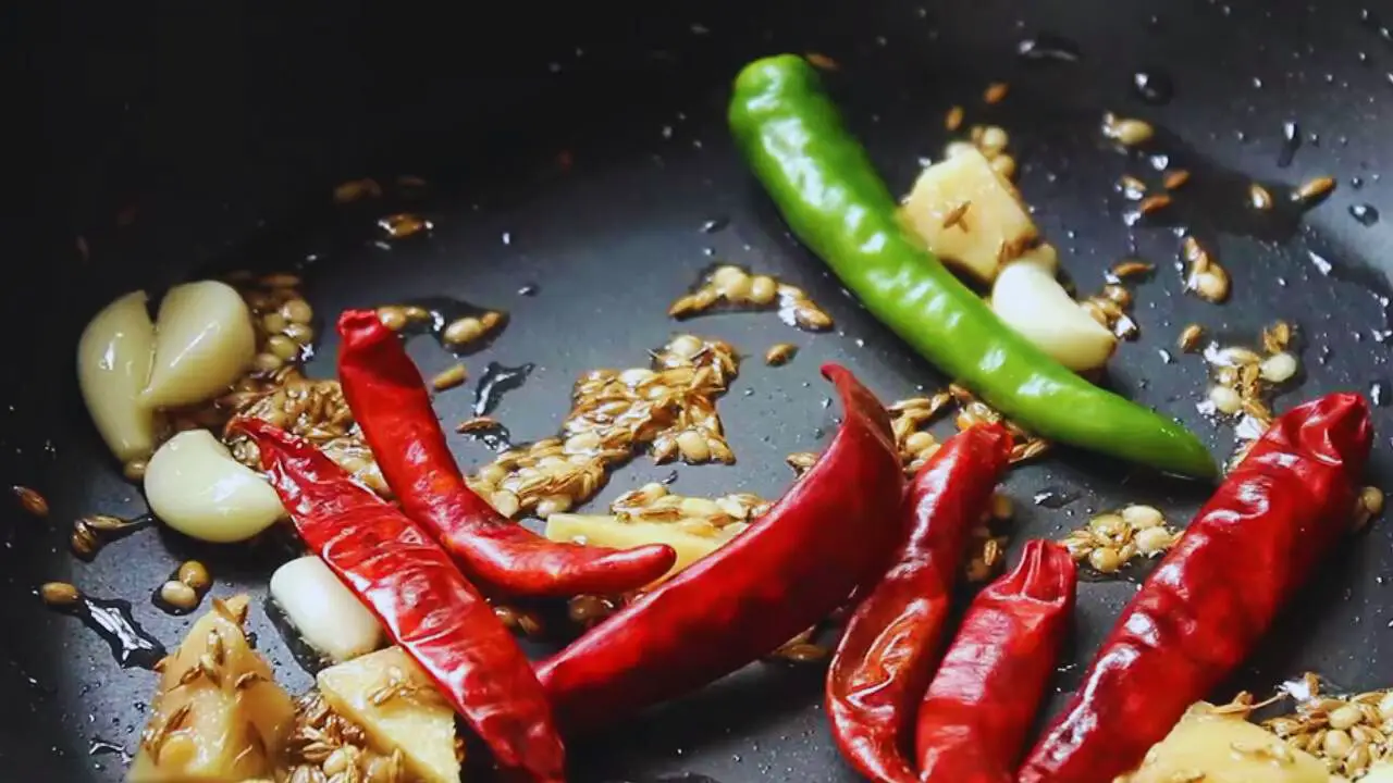 Adding 1 piece of fresh green chili and 6 pieces of dry red chilies