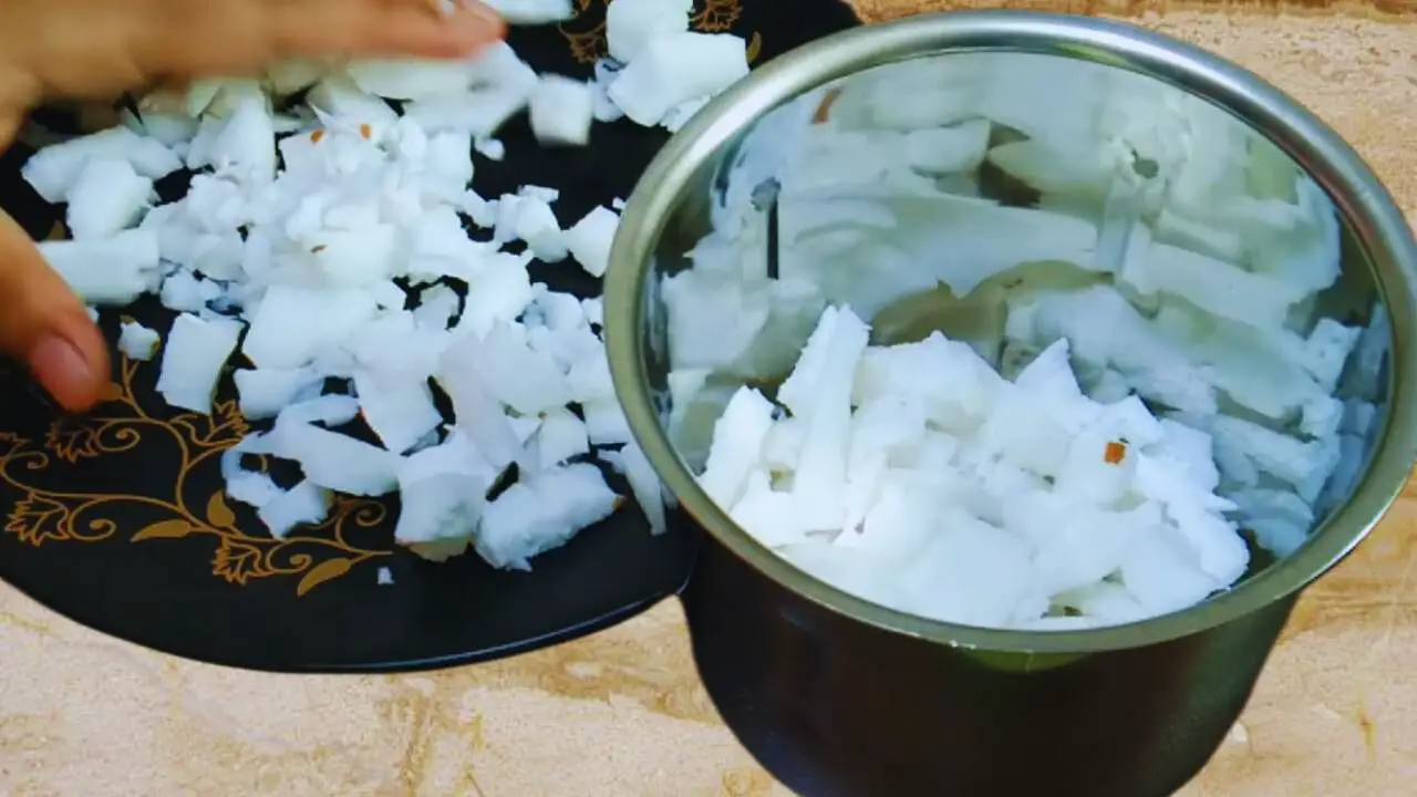 Transferring the coconut slices from the plate to the grinder