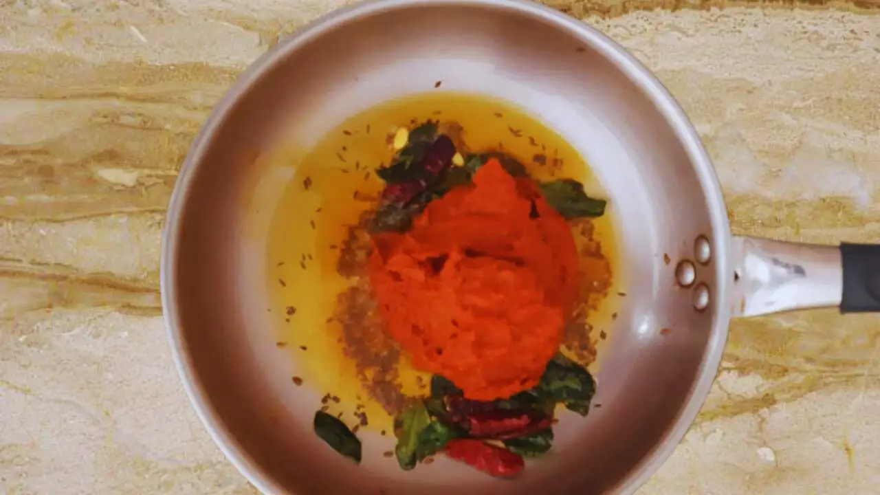 Adding the chutney paste in small portions to the fried spices