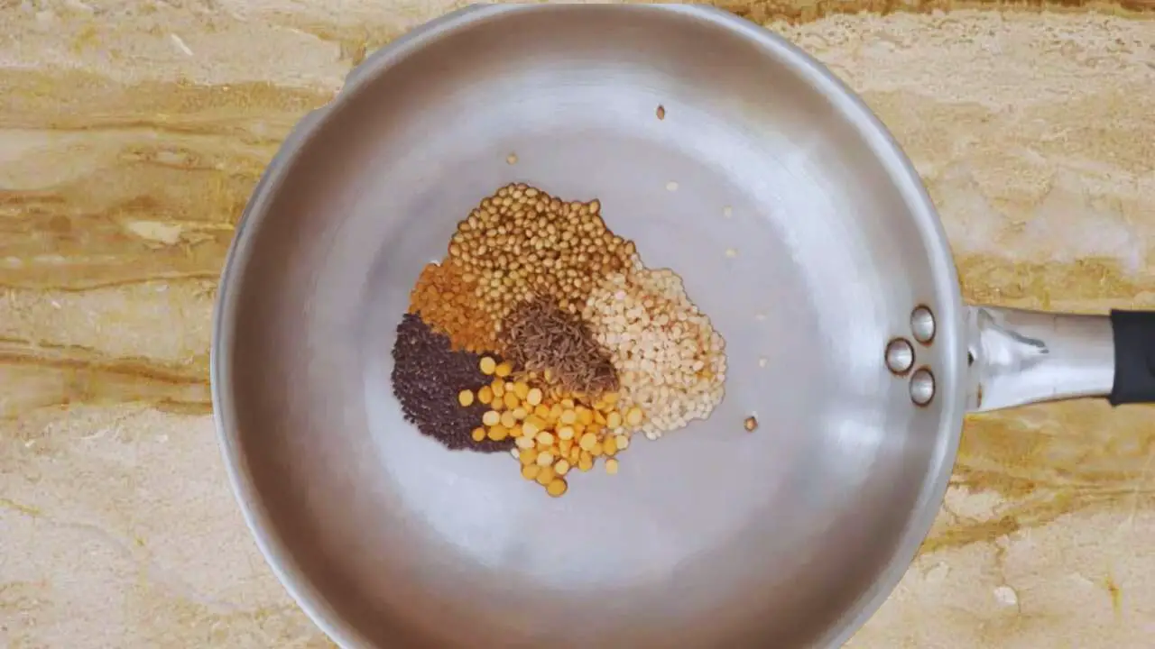 Putting ½ tsp of mustard seeds, ¼ tsp of fenugreek seeds, 1 tbsp of coriander seeds, 1 tbsp of black gram split (urad dal), 1 tbsp of split chickpeas (chana dal), and 1 tsp of cumin seeds in frying pan