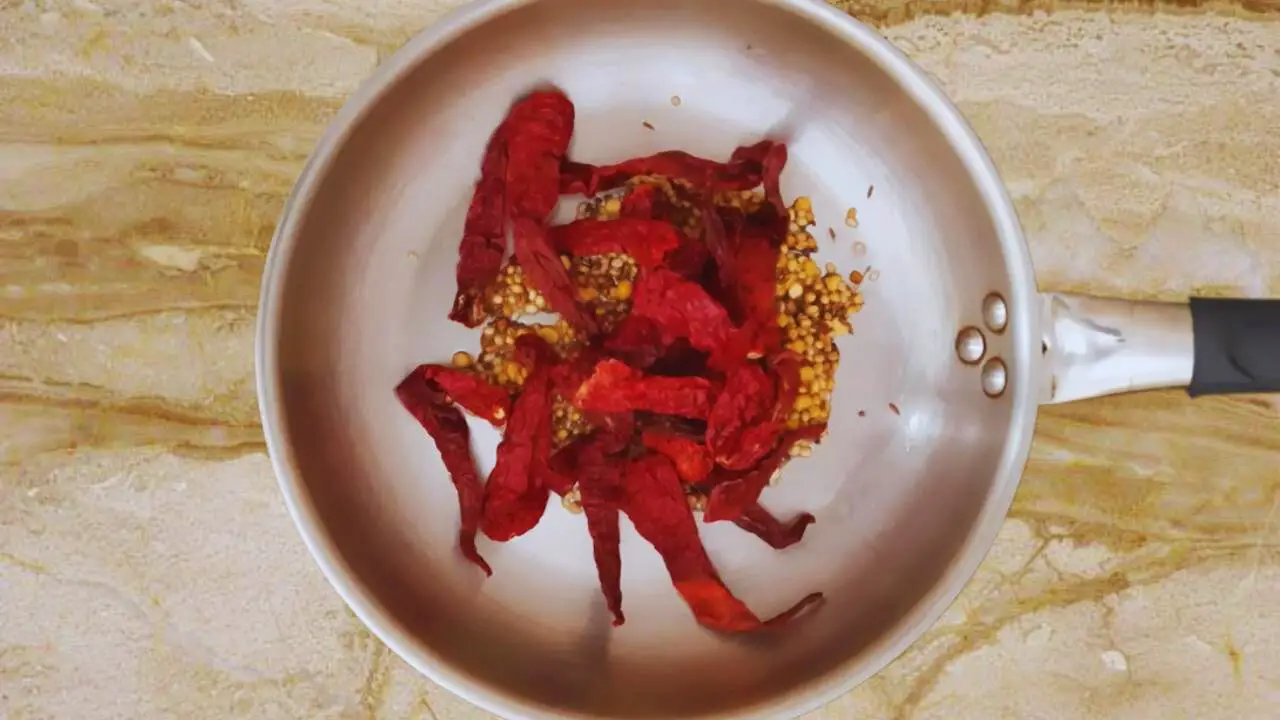 Putting dry red chilies into the pan