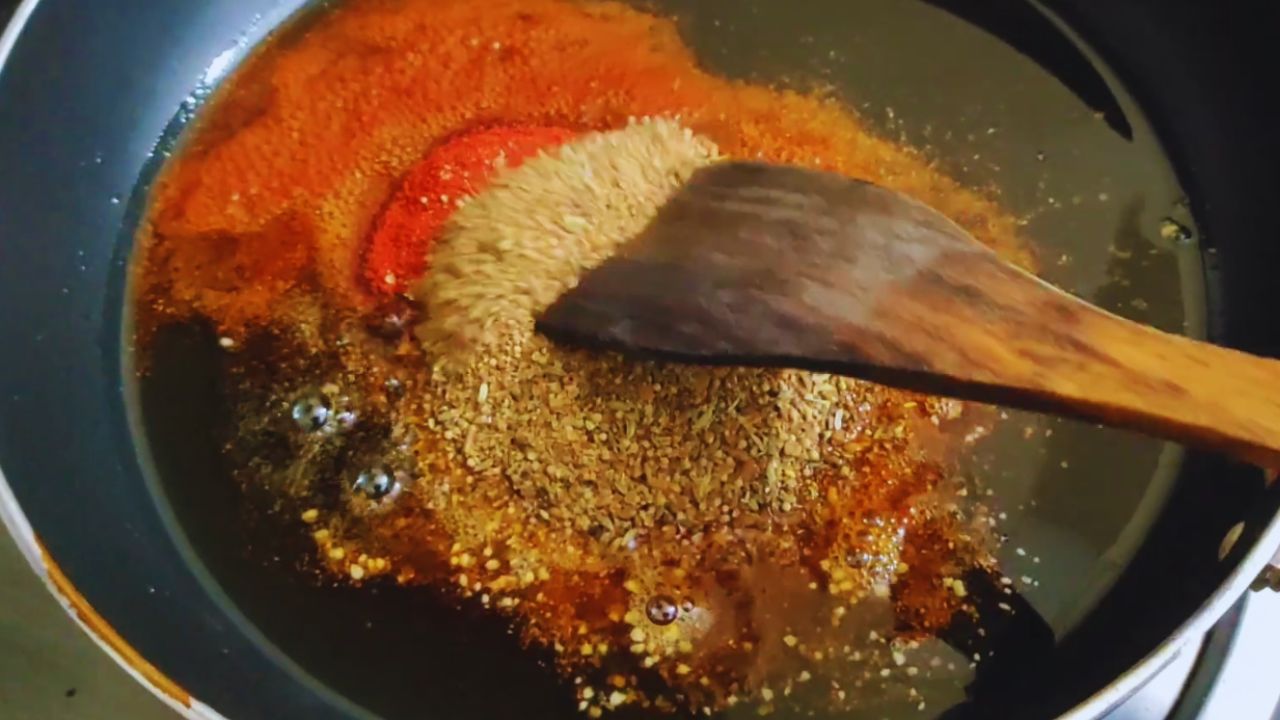 Adding nigella seeds, Kashmiri red chili powder a pinch of Asafoetida and the ground whole spice mix