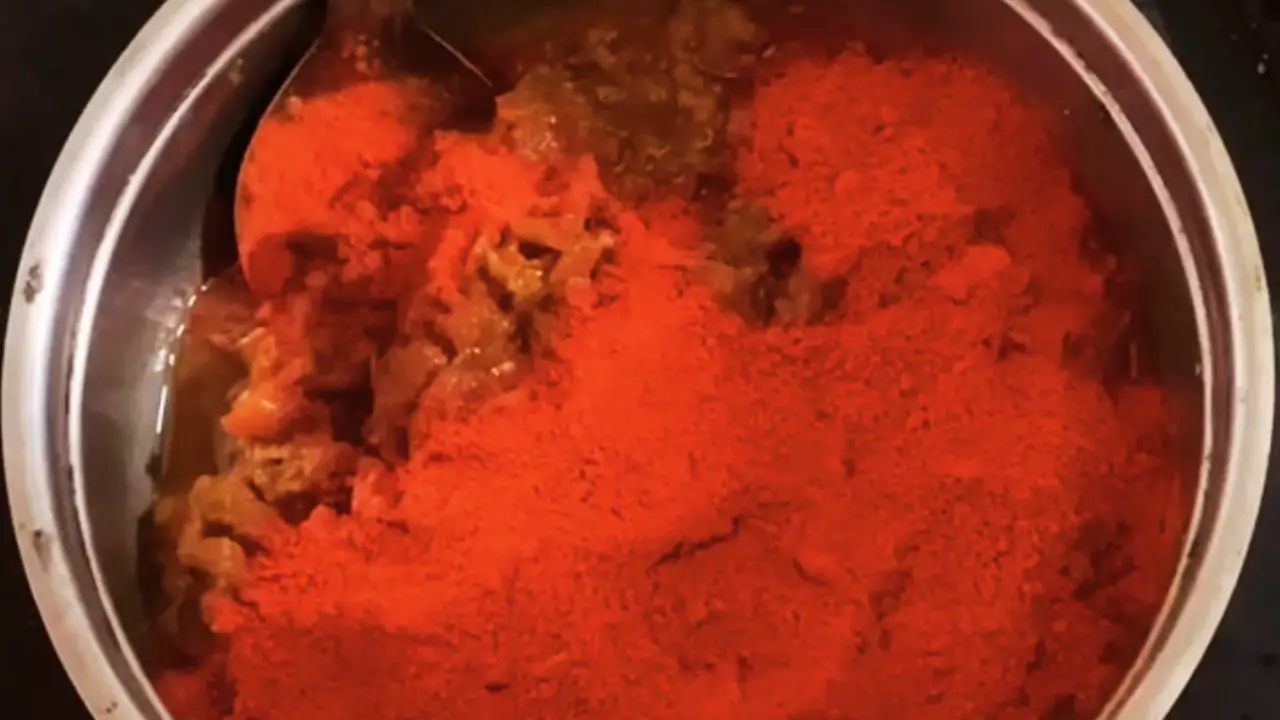 Adding 6 tbsp of red chili powder to the tomato paste