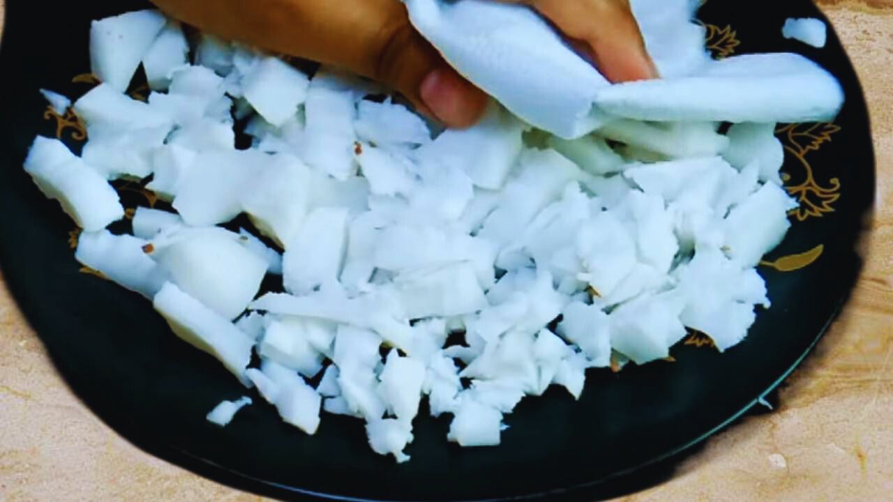 Using a tissue to remove additional water from the coconut pieces