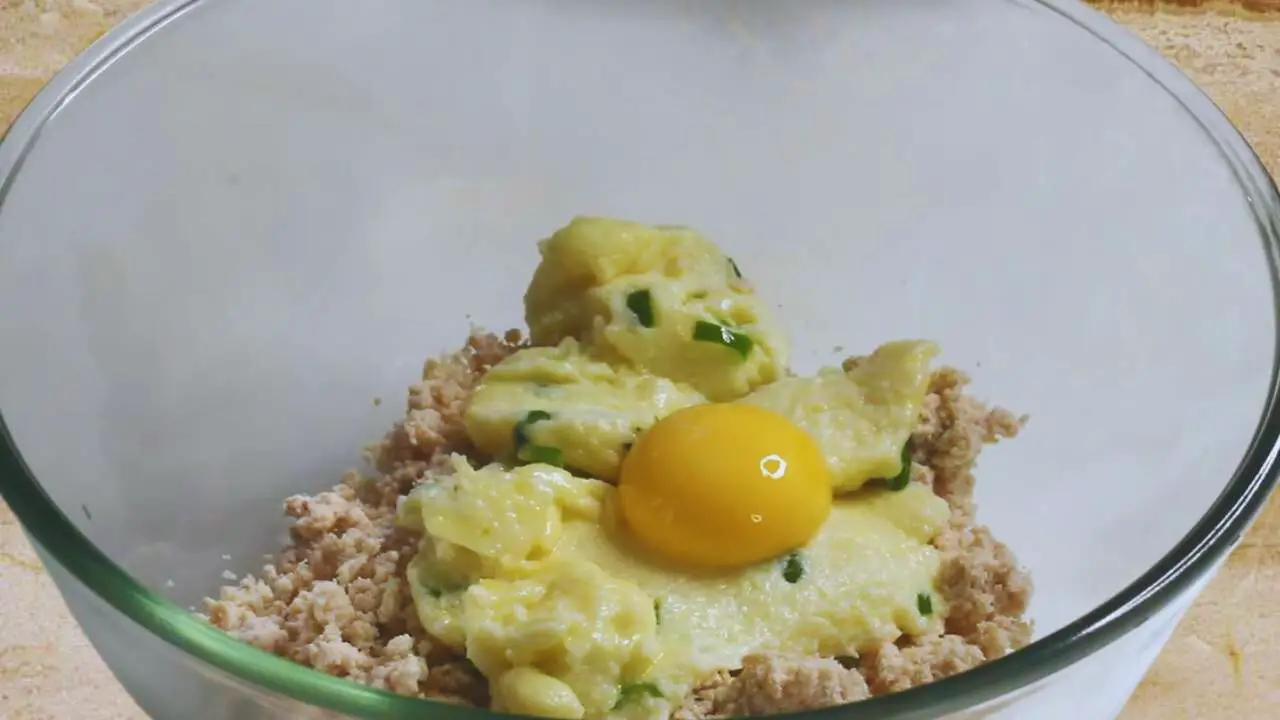 Adding egg yolk to the chicken finger mixture 