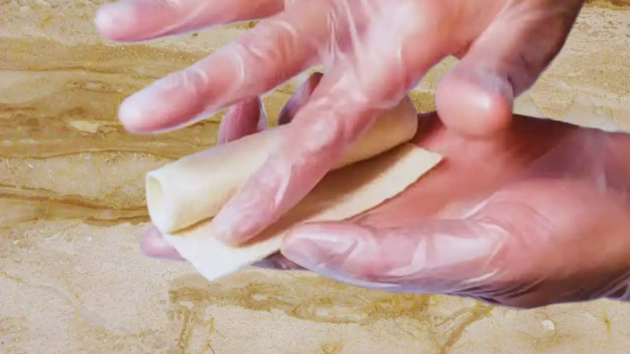 Applying water on bread to close cheese stick