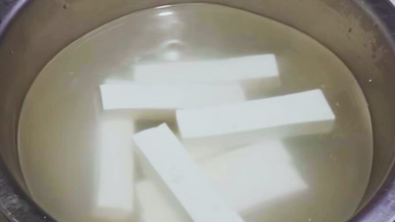 Dipping paneer fingers in salt and water to balance moisture and salt content 