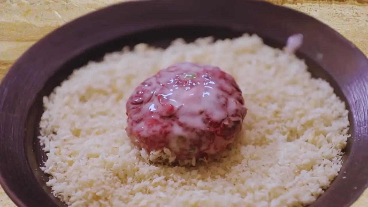 Putting beetroot cutlet in bread crumbs 
