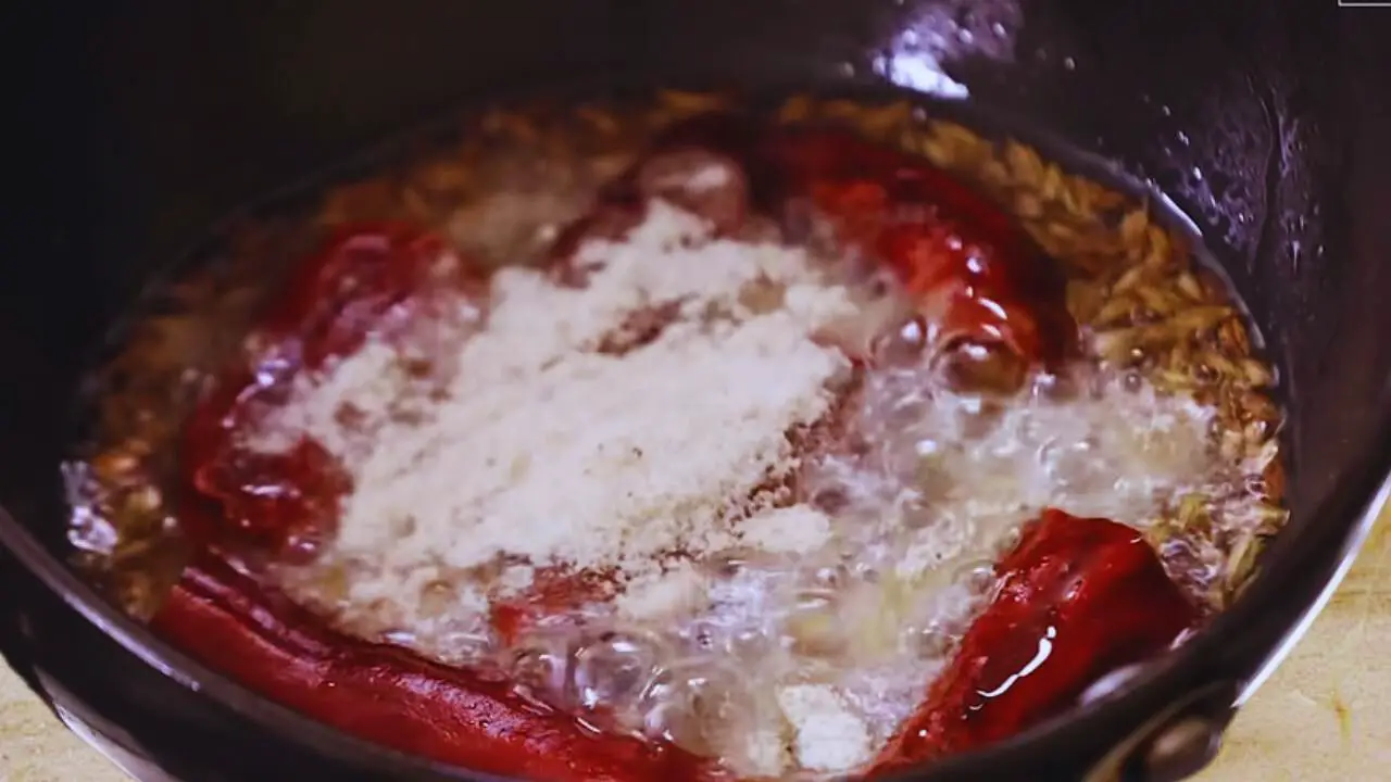 Adding asafetida to peanut chutney tadka 