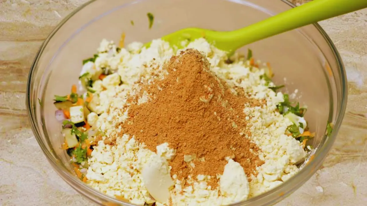 Adding chat masala to the Vegetable Pakora mixture 
