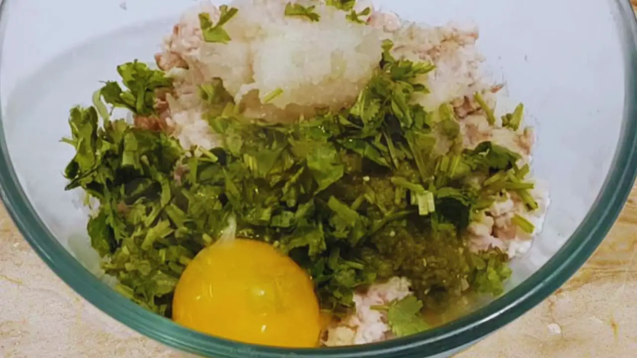 adding coriander leaves and egg yolk to Fish Cutlet ingredients 
