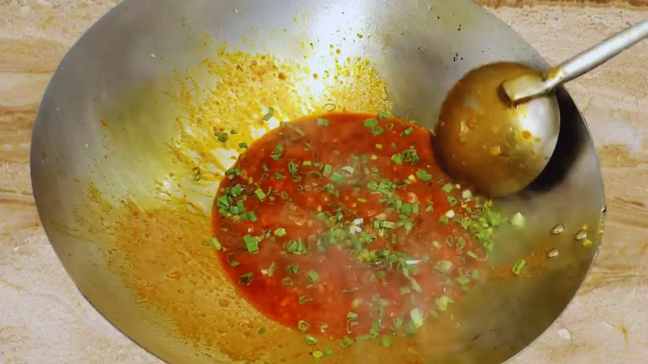 Adding coriander leaves to chicken lollipop sauce 