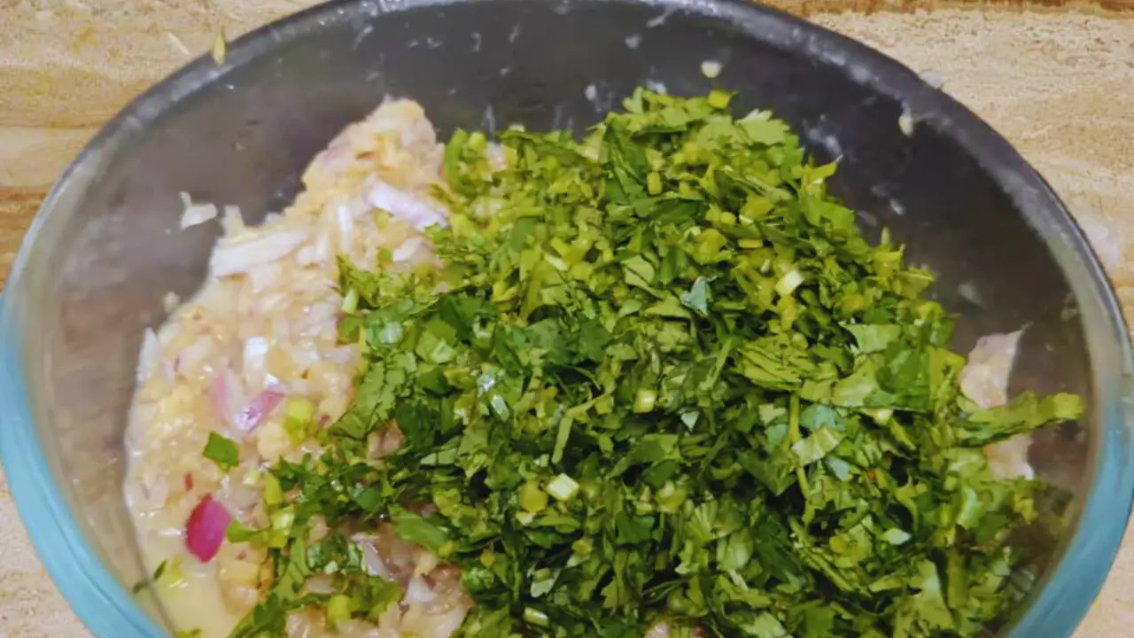 Adding coriander leaves to Fish Momo ingredients 
