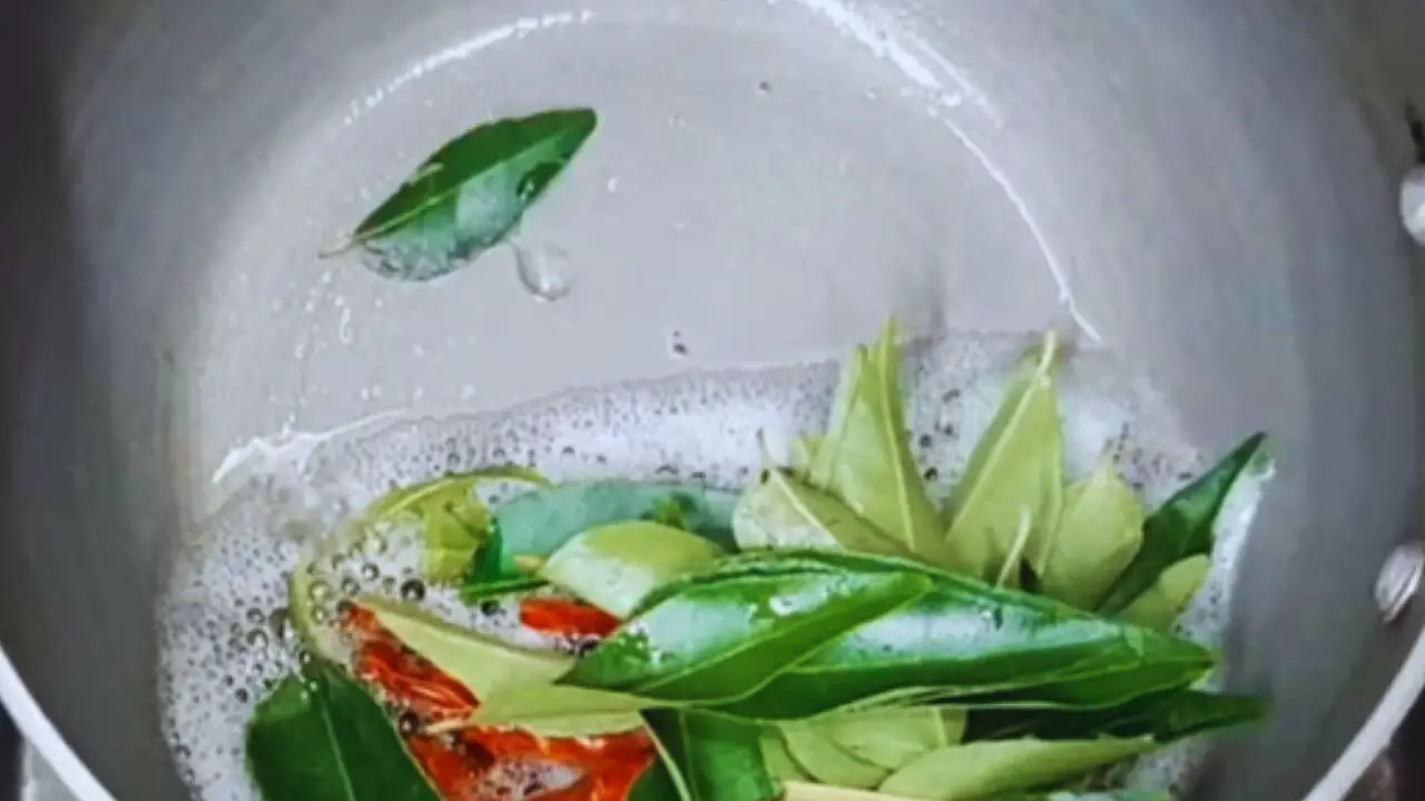 Adding curry leaves to make the tadka for Dahi Chutney
