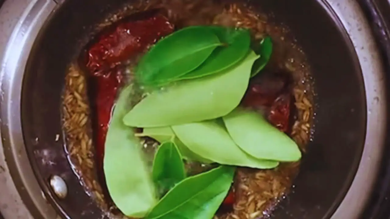 Adding curry leaves to peanut chutney tadka 