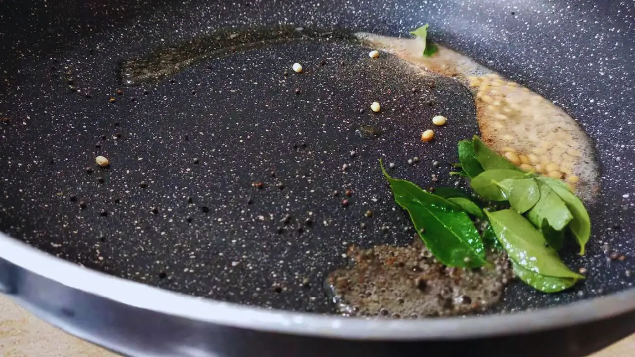 Adding curry leaves to the onion tomato chutney tadka 
