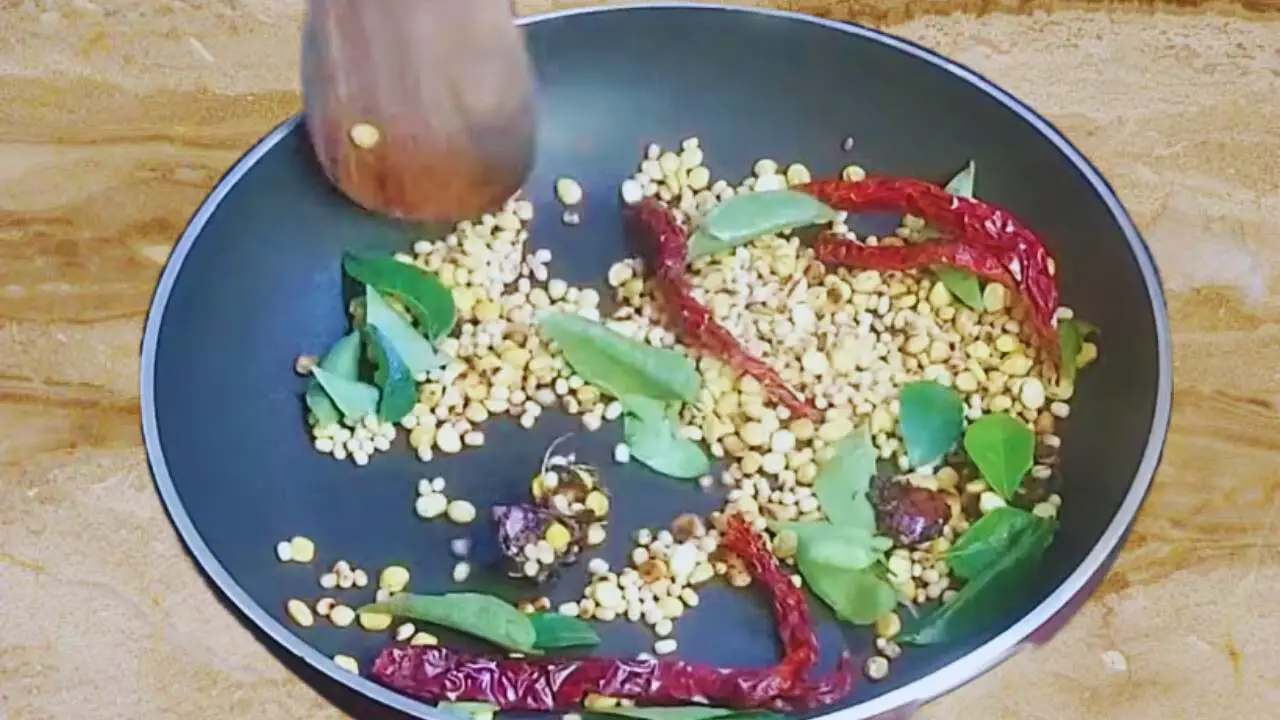 Adding curry leaves to the spices of Cauliflower Chutney 